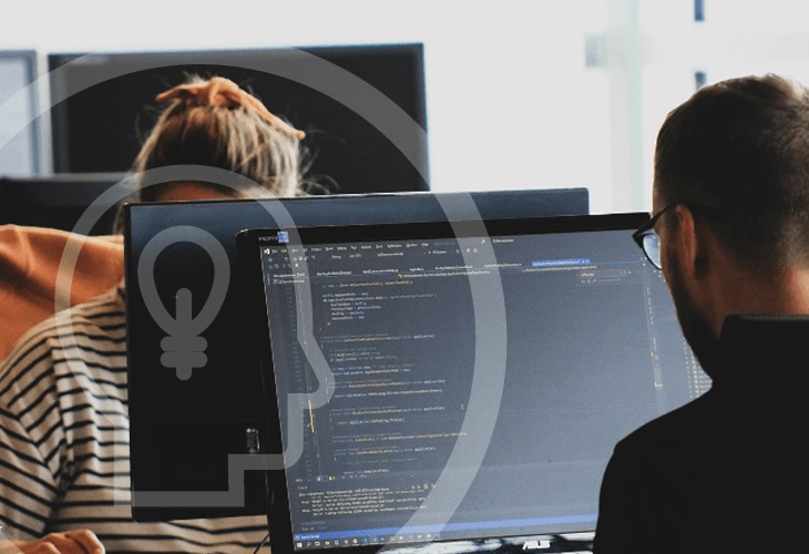 Två presoner som sitter vid sina datorer. Ppå skärmen syns kod. Över bilden finns en symbol föreställande ett huvud i profil med en glödlampa i.